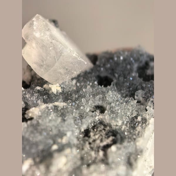 Single quartz crystal on matrix with small biscuit calcite crystals — detail view