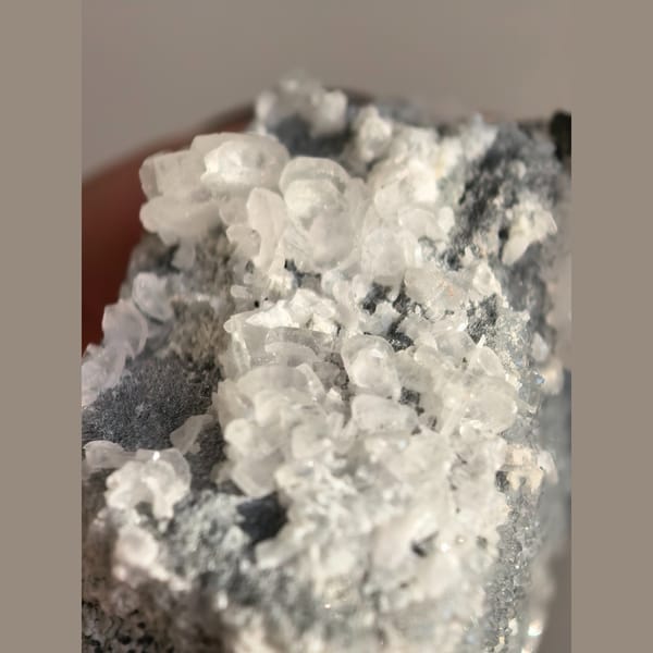 Single quartz crystal on matrix with small biscuit calcite crystals — detail view