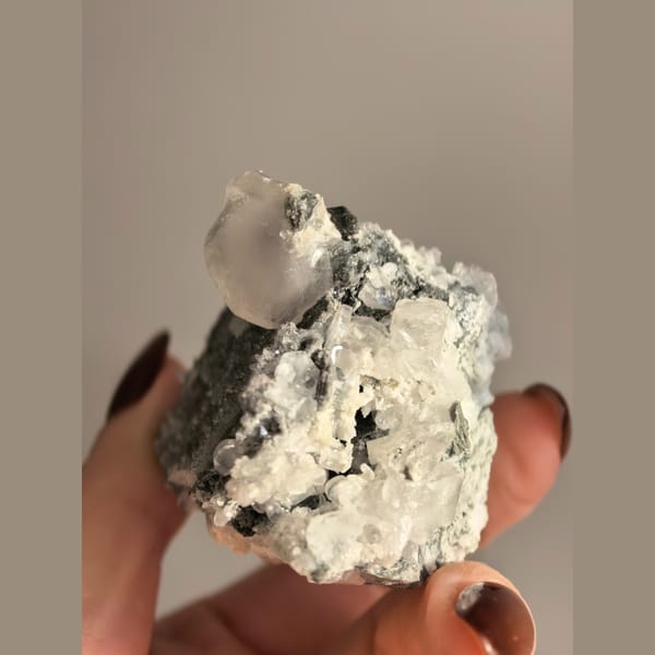 Single quartz crystal on matrix with small biscuit calcite crystals — detail view