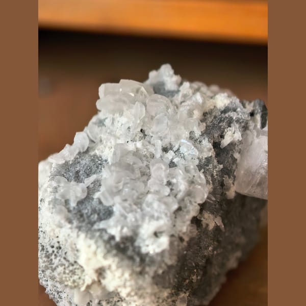 Single quartz crystal on matrix with small biscuit calcite crystals — detail view