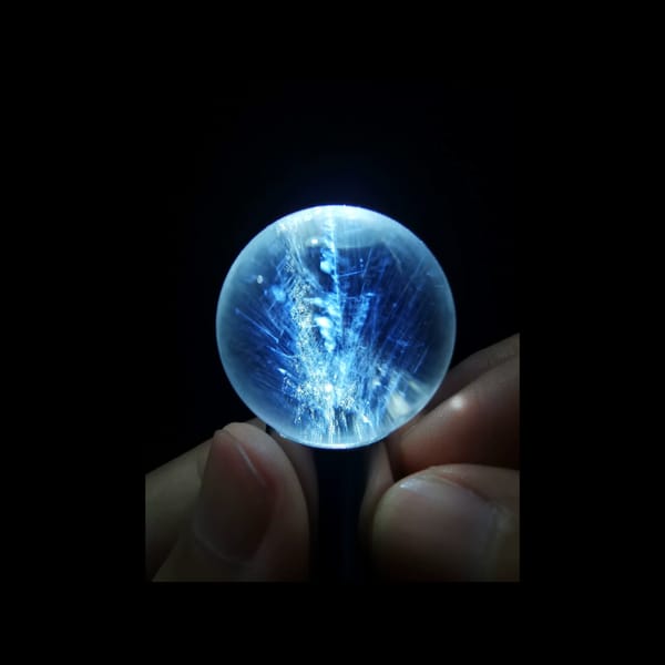 Clear quartz sphere with blue needle inclusions — complete view