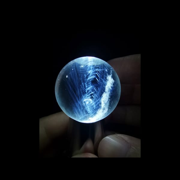 Clear quartz sphere with blue needle inclusions — alternate view