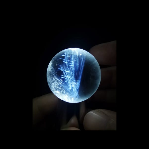 Clear quartz sphere with blue needle inclusions — alternate view