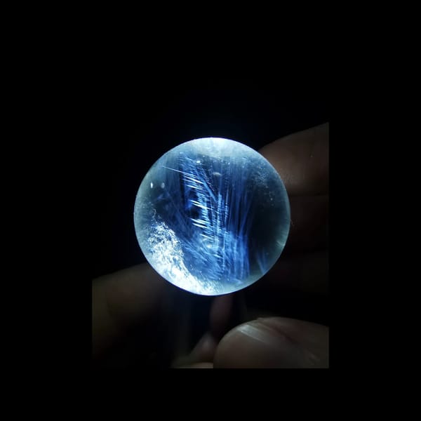 Clear quartz sphere with blue needle inclusions — detail view