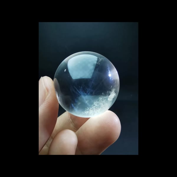 Clear quartz sphere with blue needle inclusions — detail view