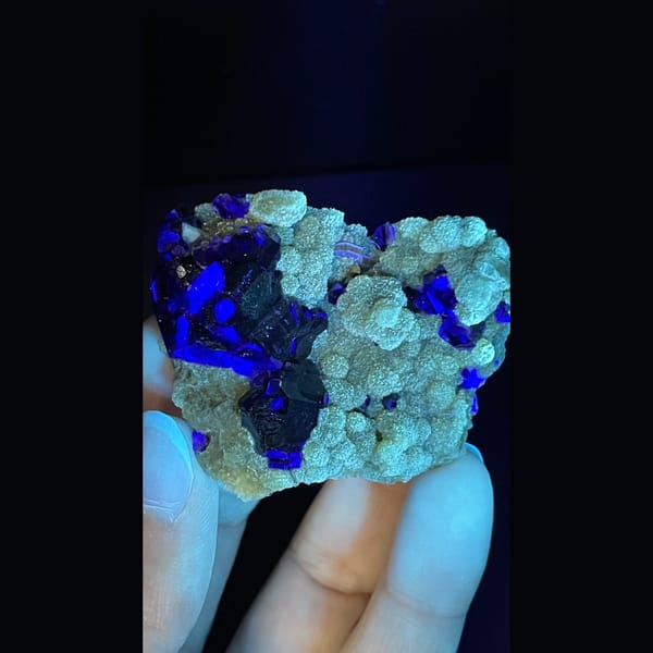 Dark apatite with purple fluorite on yellow-green mica from Inner Mongolia — detail view