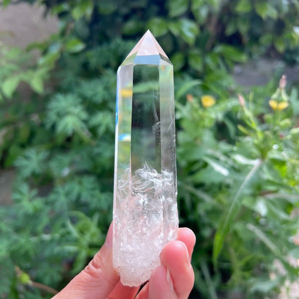 Tall clear quartz point with white phantoms and blue needle inclusions — detail view