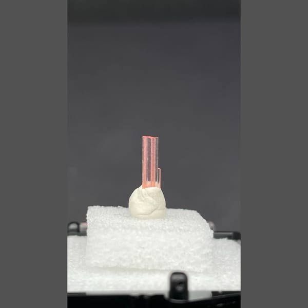 Tiny pale pink väyrynenite crystal on a display stand from Pakistan — alternate view
