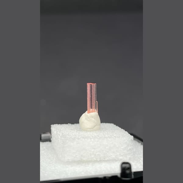Tiny pale pink väyrynenite crystal on a display stand from Pakistan — detail view