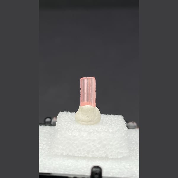 Tiny pale pink väyrynenite crystal on a display stand from Pakistan — complete view