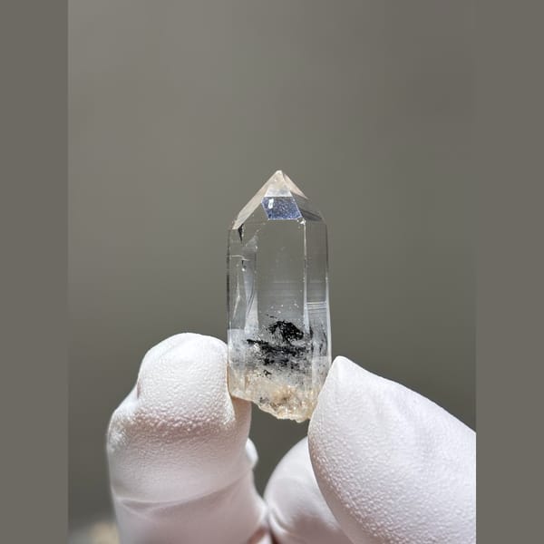 Small clear window quartz floater with dark inclusions from Jinkouhe — complete view