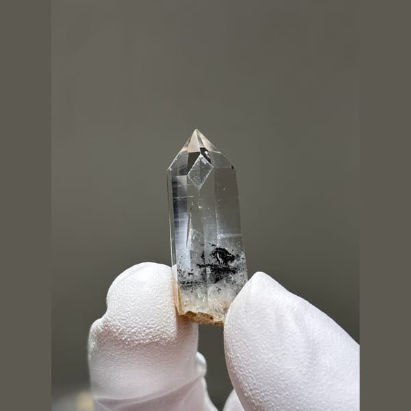 Small clear window quartz floater with dark inclusions from Jinkouhe — alternate view