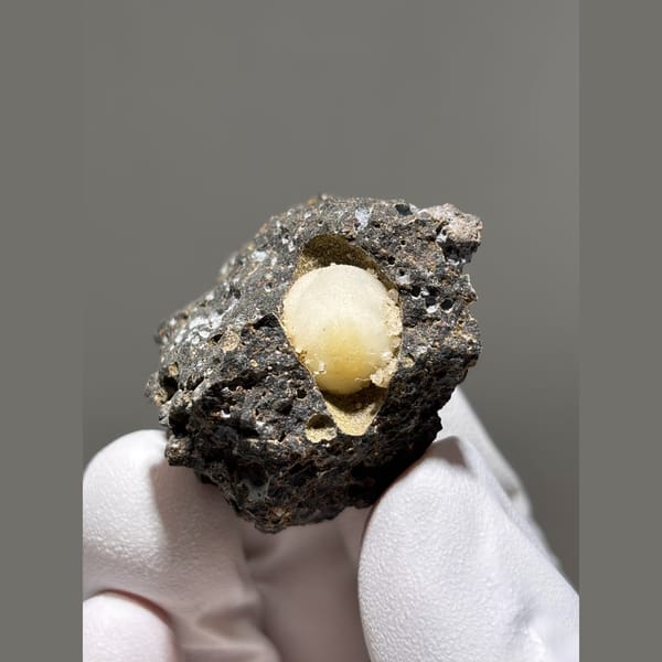 Rounded yellow calcite in a pocket of dark matrix from Zhejiang — complete view