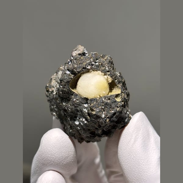Rounded yellow calcite in a pocket of dark matrix from Zhejiang — alternate view