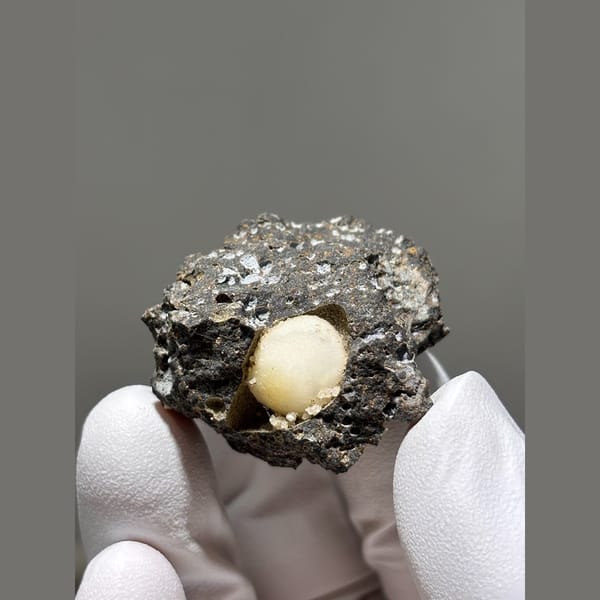 Rounded yellow calcite in a pocket of dark matrix from Zhejiang — detail view