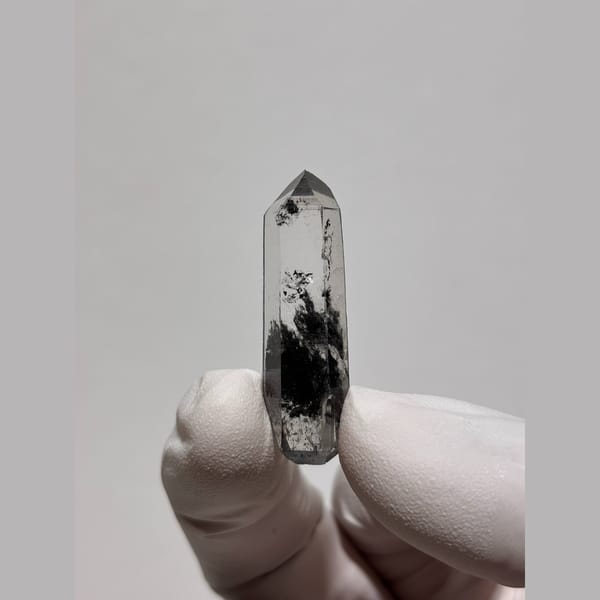 Slim clear quartz floater with black inclusions from Jinkouhe — complete view