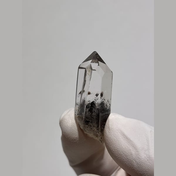 Slender clear quartz point with dark inclusions from Jinkouhe — alternate view