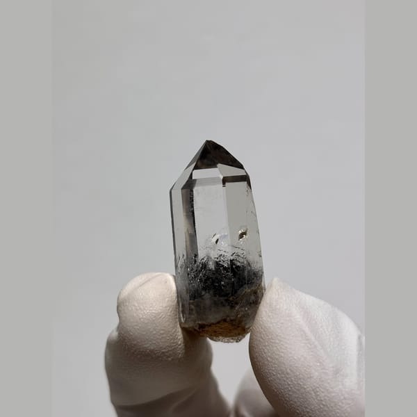 Slender clear quartz point with dark inclusions from Jinkouhe — alternate view