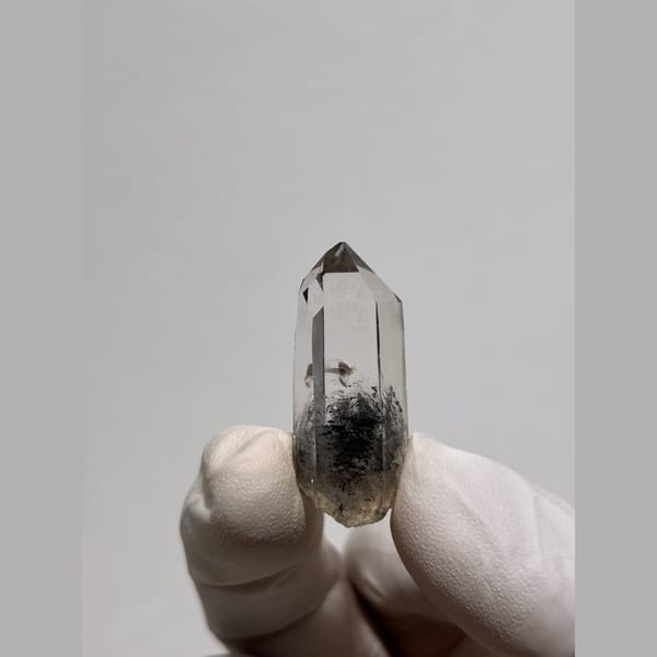 Slender clear quartz point with dark inclusions from Jinkouhe — detail view