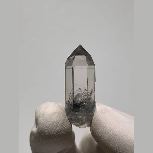 Small clear quartz point with dark inclusions from Jinkouhe — complete view