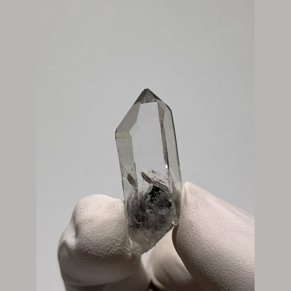 Small clear quartz point with dark inclusions from Jinkouhe — detail view