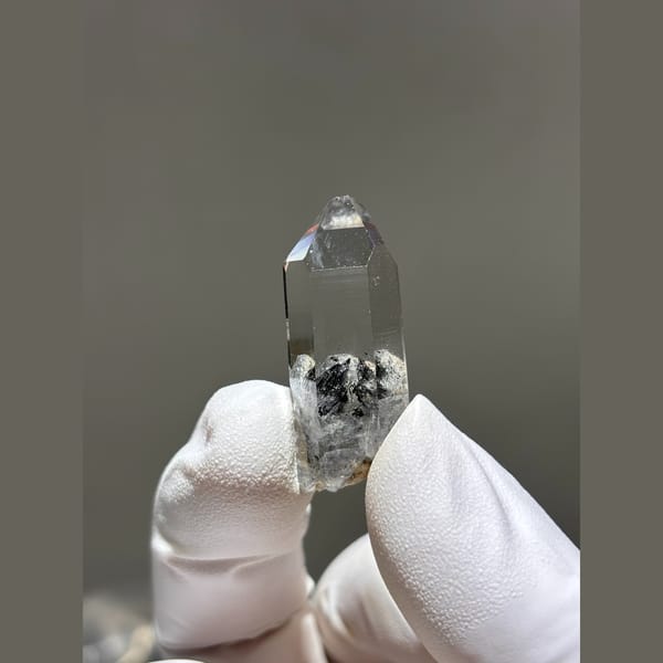 Clear quartz point with dark inclusions from Jinkouhe — complete view
