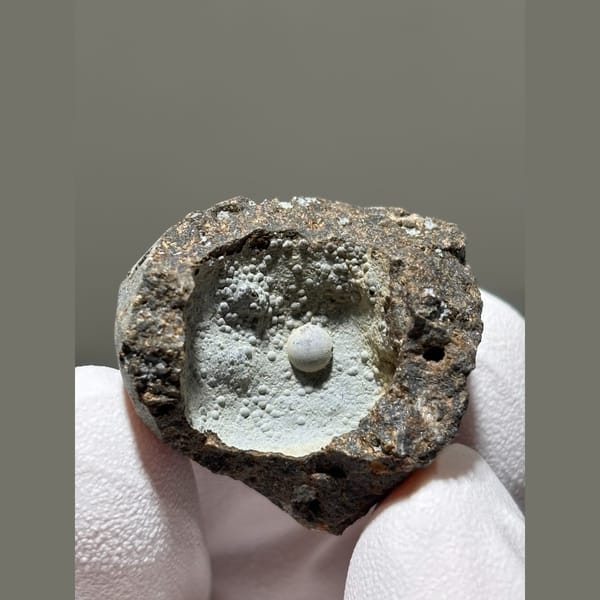 Tiny calcite pearl in a frosty matrix pocket from Zhejiang — complete view
