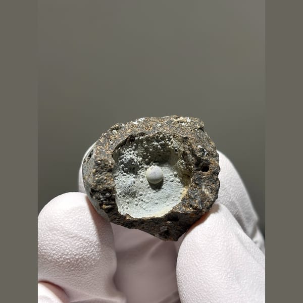 Tiny calcite pearl in a frosty matrix pocket from Zhejiang — alternate view