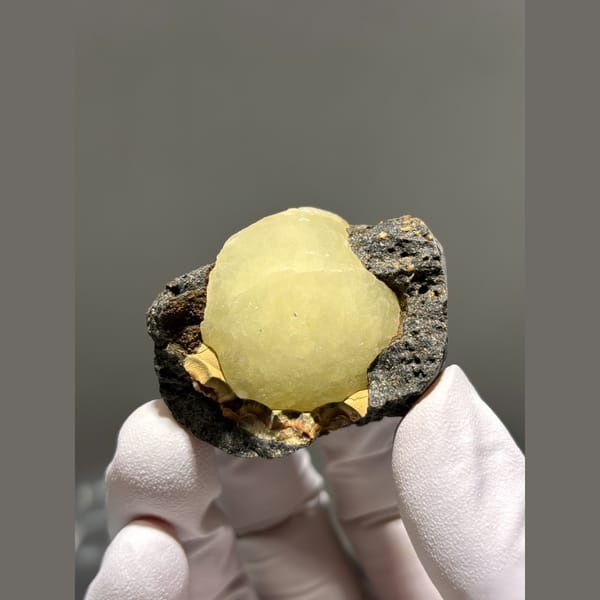 Pale yellow calcite ball in dark matrix pocket from Zhejiang — complete view