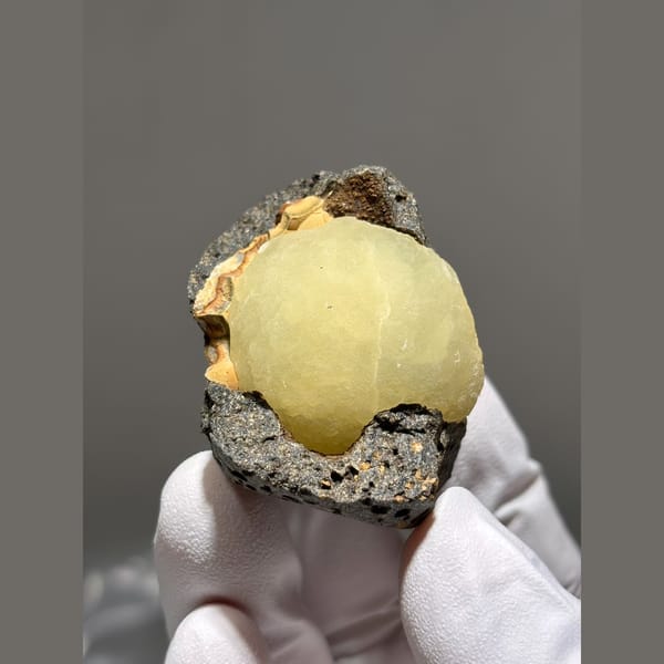 Pale yellow calcite ball in dark matrix pocket from Zhejiang — alternate view