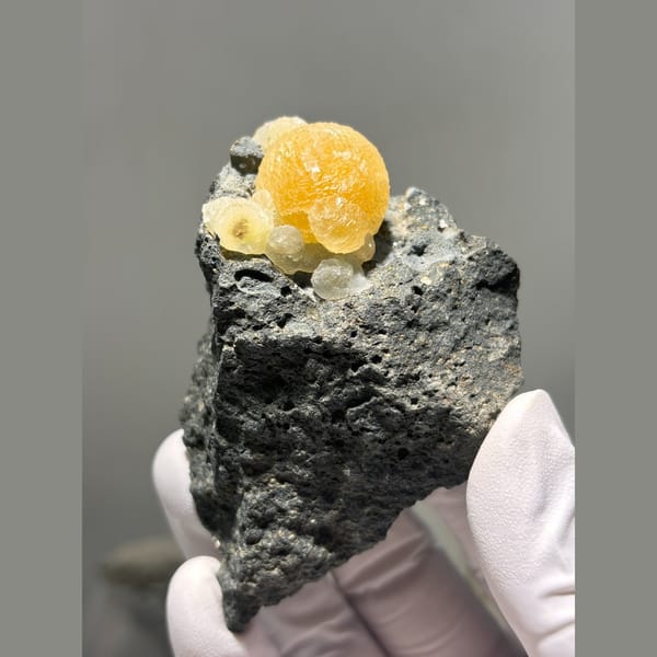 Bright yellow calcite sphere in dark matrix from Zhejiang — complete view