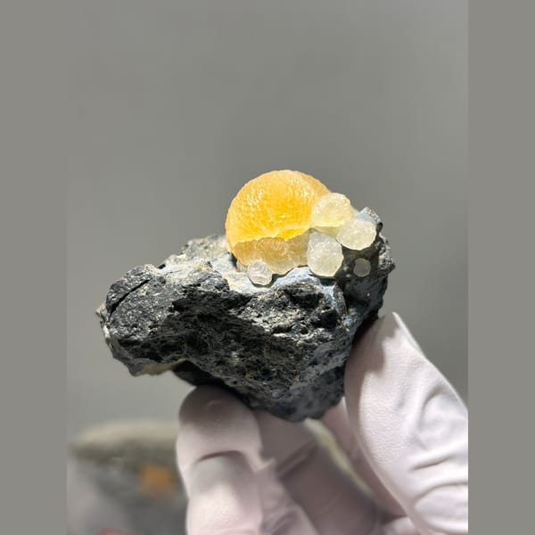 Bright yellow calcite sphere in dark matrix from Zhejiang — alternate view