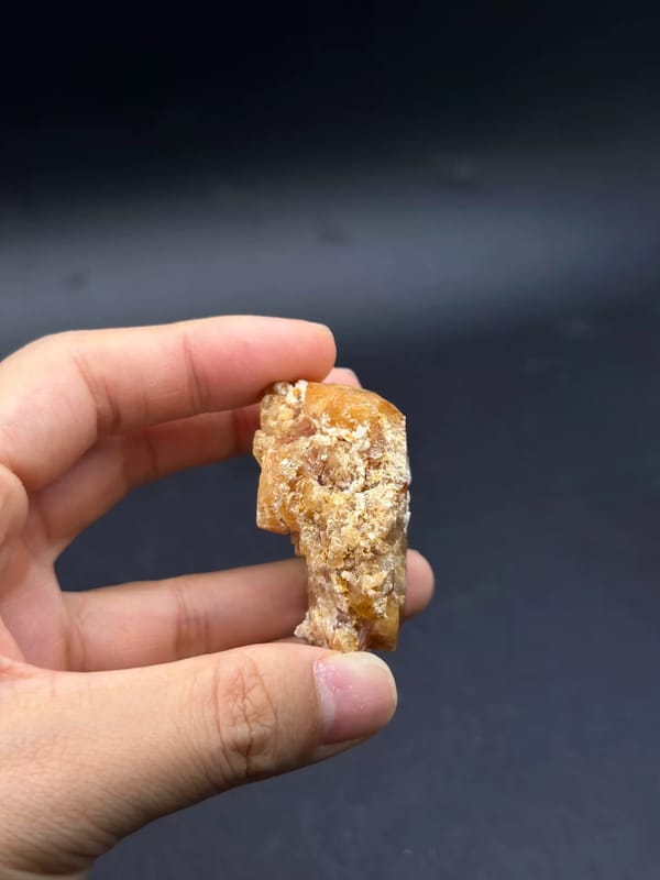Complete thin side profile of the scheelite specimen held between fingertips