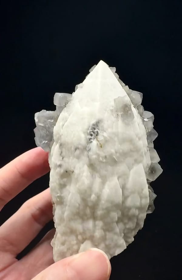 Complete white quartz reverse with fluorite crystals at both sides, handheld at the lower edge