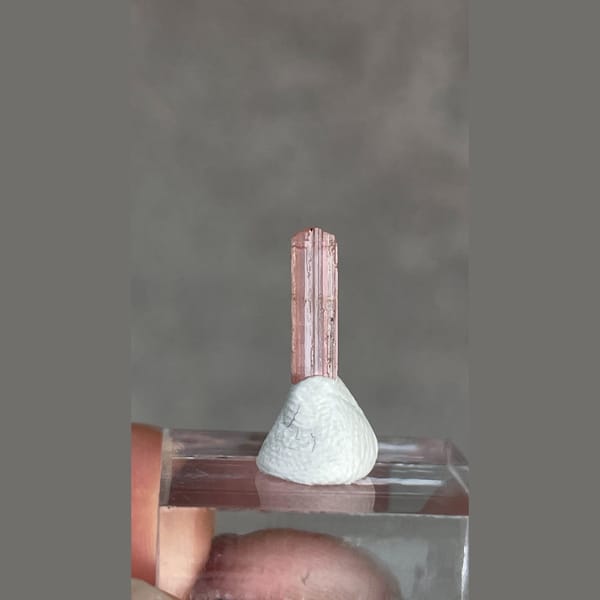 Tiny pale pink väyrynenite crystal from Pakistan on a stand — complete view