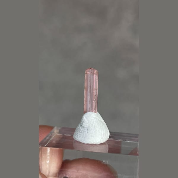 Tiny pale pink väyrynenite crystal from Pakistan on a stand — alternate view