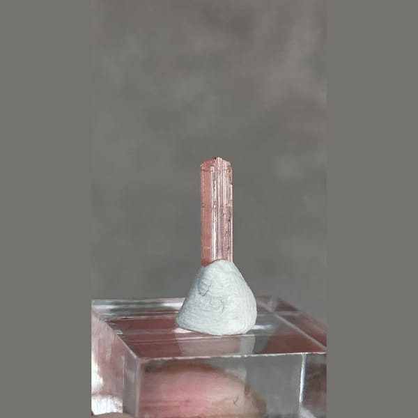 Tiny pale pink väyrynenite crystal from Pakistan on a stand — alternate view
