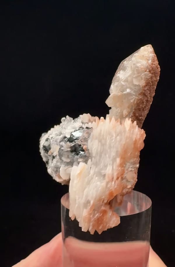 Complete narrow side with pale calcite blades and a quartz termination behind