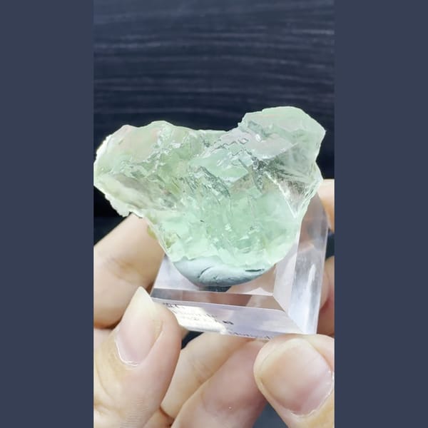 Glassy jelly-green fluorite crystal on an acrylic stand from Chifeng, Inner Mongolia — complete view