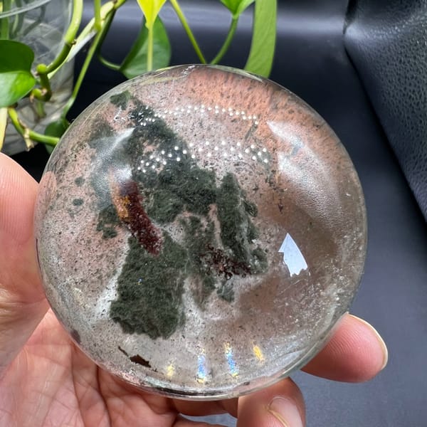 Clear quartz sphere with green phantoms and a moving water bubble from Brazil — detail view