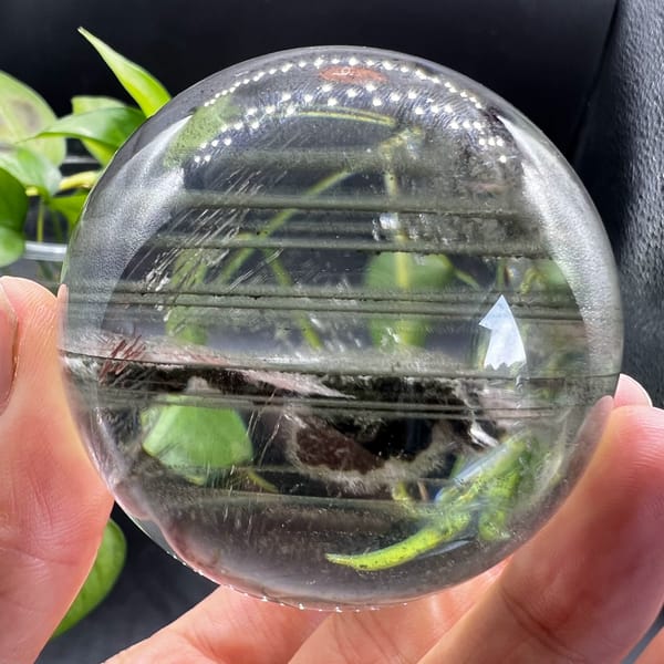 Clear quartz sphere with green phantoms and a moving water bubble from Brazil — detail view