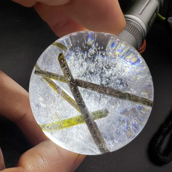 Clear quartz sphere with green tourmaline inclusions — complete view