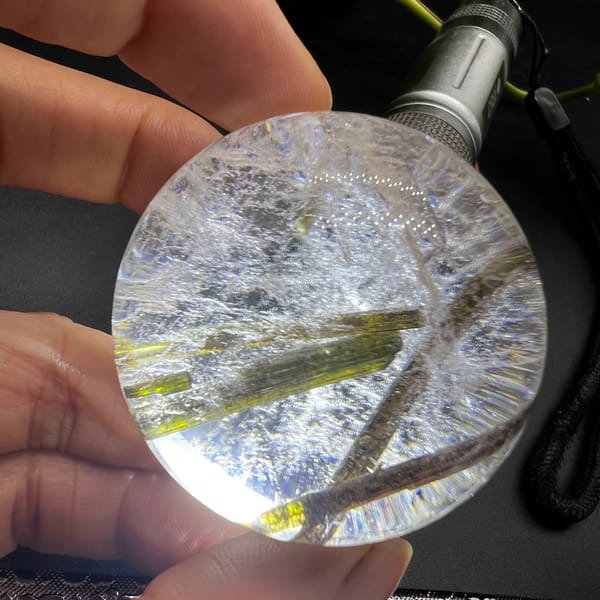 Clear quartz sphere with green tourmaline inclusions — alternate view