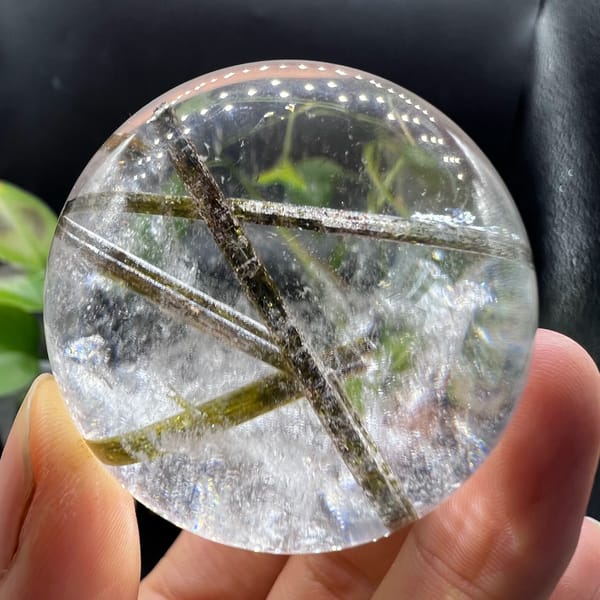 Clear quartz sphere with green tourmaline inclusions — detail view