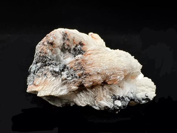 Complete low side view showing the pale layered calcite and dark specular hematite base