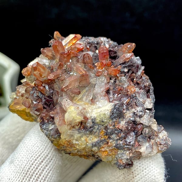Red-orange quartz points on dark specular hematite from Guangdong — detail view