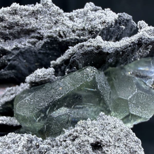 Green fluorite in hollows of a layered quartz-coated matrix from Fujian — detail view