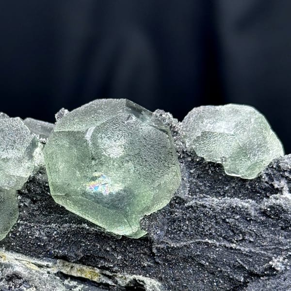 Rounded pale green fluorite on dark quartz-coated matrix from Fujian — detail view