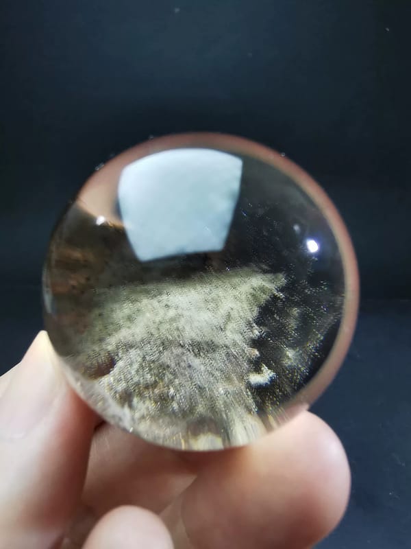 Complete rotated view showing the pale ghost inclusion rising diagonally through the quartz sphere