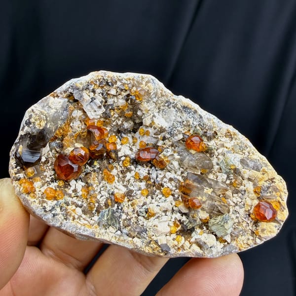 Complete crystal-bearing face of orange garnet with smoky quartz